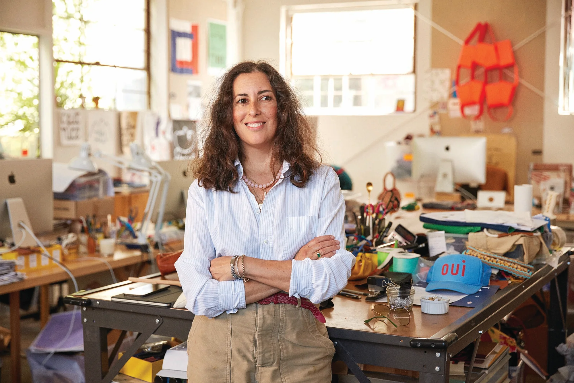 Conqueror standing in front of a desk smiling with her arms crossed. She's in her studio located in Los Angeles, CA. 