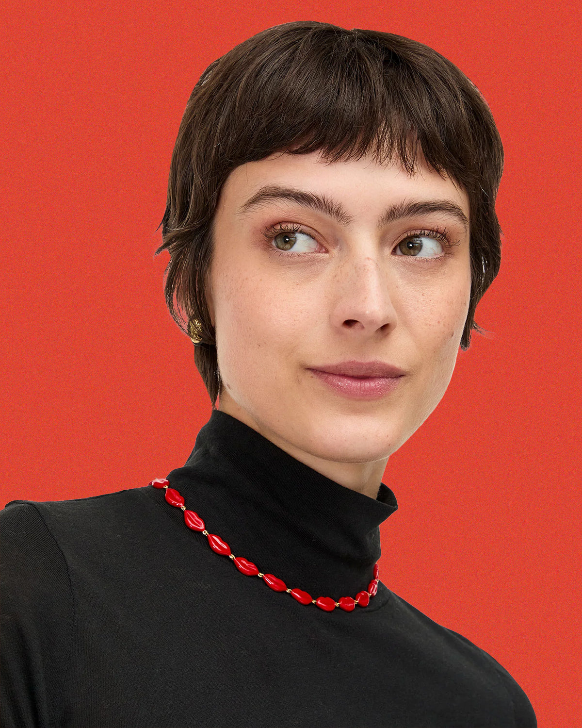 Model wearing the Le Lips Necklace over her black turtleneck. 